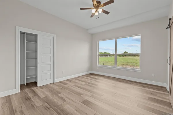 a view of an empty room with a window and wooden floor