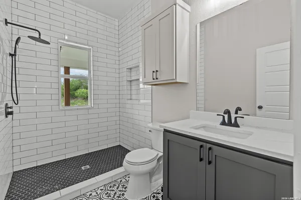 a bathroom with a granite countertop toilet sink and mirror