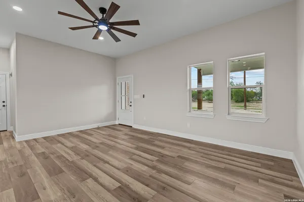 a view of empty room with wooden floor and fan