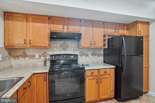 a kitchen with granite countertop a refrigerator stove and cabinets