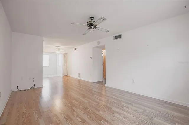 a view of a room with wooden floor and a ceiling fan