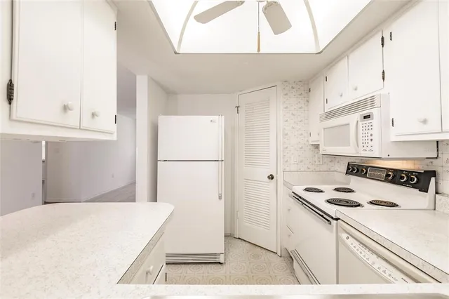 a kitchen with kitchen island a stove a refrigerator a sink a counter space and cabinets