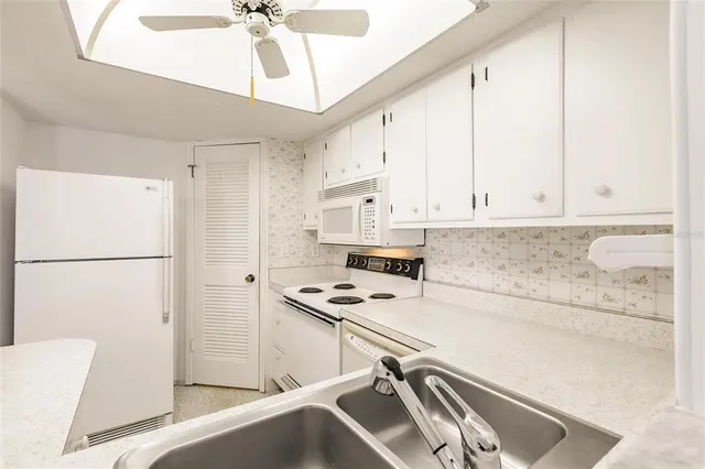 a kitchen with stainless steel appliances a refrigerator a stove a sink and white cabinets