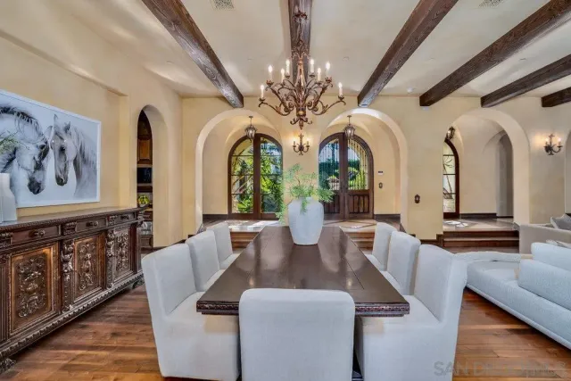 a dining room with wooden floor a chandelier a wooden table and chairs