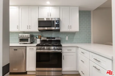 a kitchen with white cabinets and stainless steel appliances