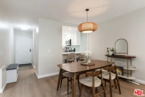 a dining room with wooden floor a chandelier a wooden table and chairs