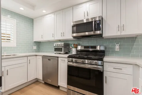 a kitchen with stainless steel appliances granite countertop grey cabinets a stove a sink and dishwasher