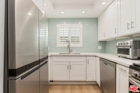 a kitchen with white cabinets and appliances