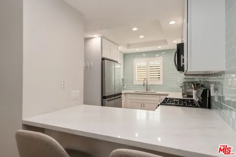 a kitchen with stainless steel appliances a refrigerator a sink a stove a dining table and chairs