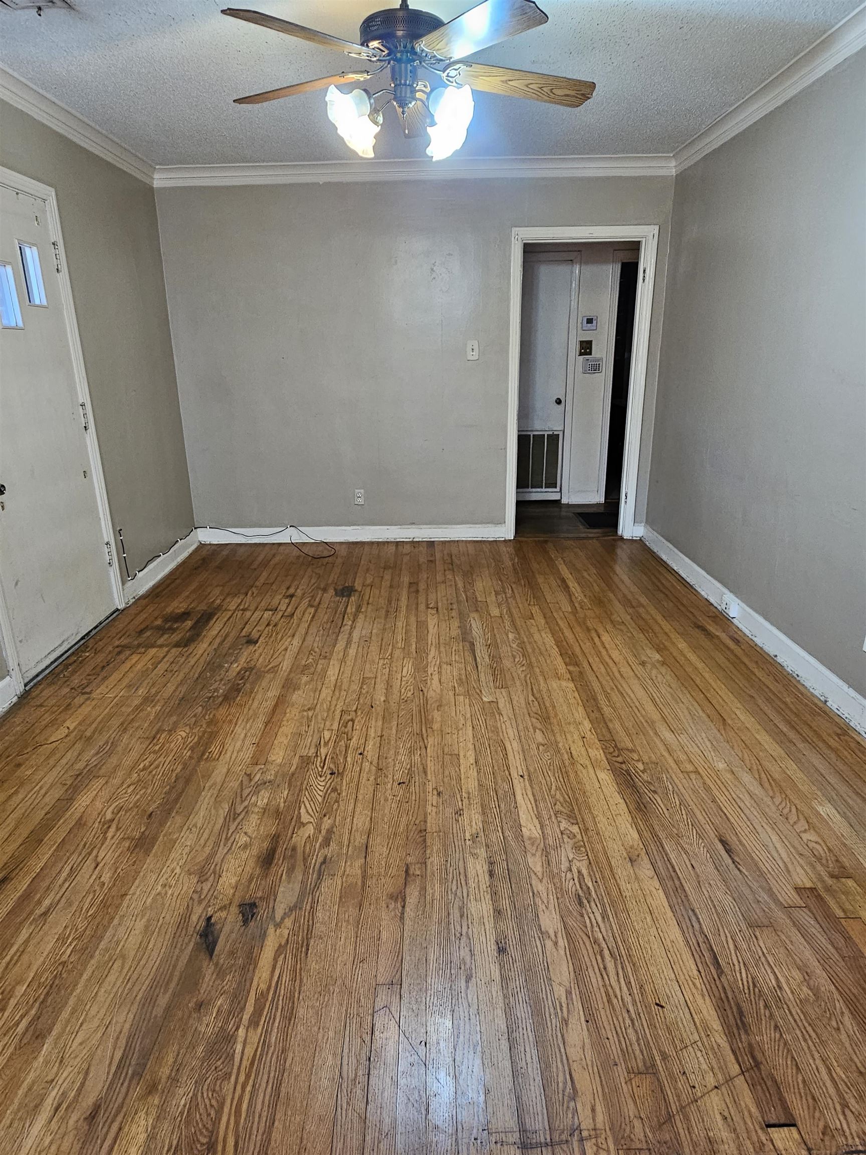 1196 Wells Station Road Memphis, TN 38122 - Photo 12 of 20 Unfurnished room with a textured ceiling, ornamental molding, hardwood / wood-style floors, and ceiling fan