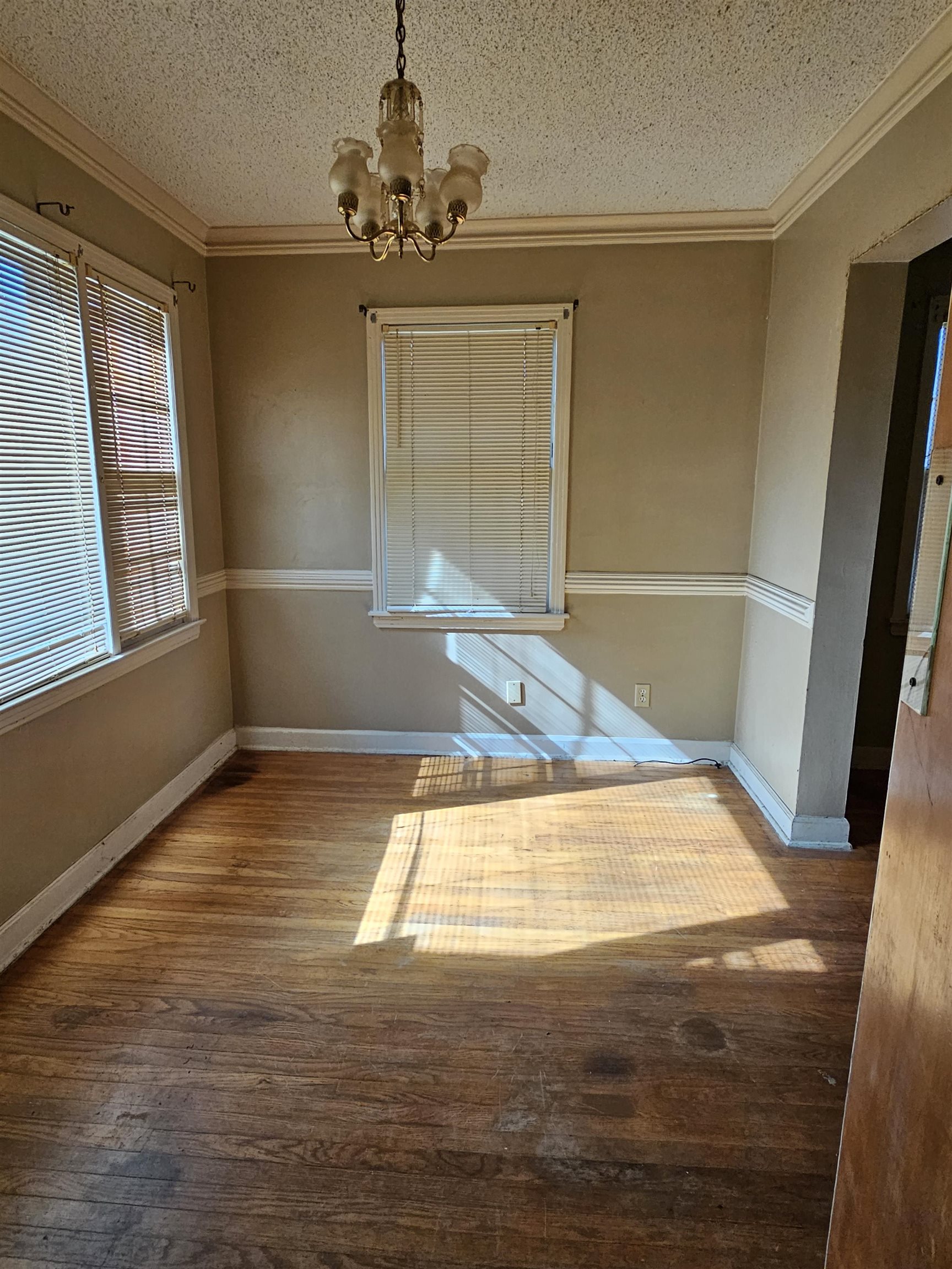 1196 Wells Station Road Memphis, TN 38122 - Photo 14 of 20 Unfurnished dining area with a textured ceiling, dark wood-style floors, crown molding, and a chandelier