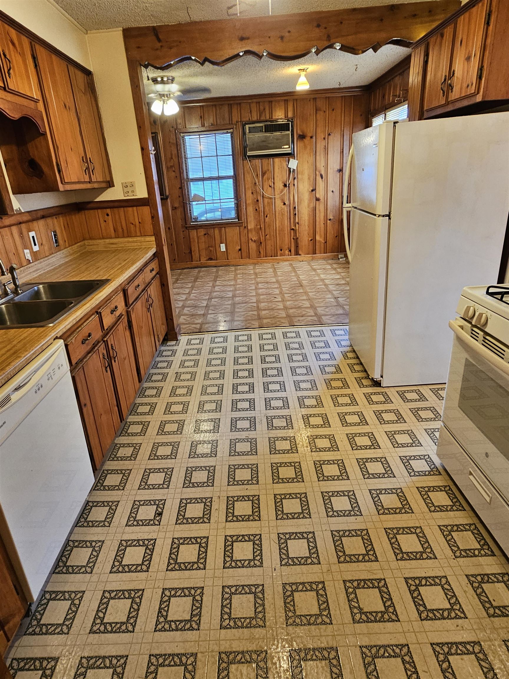 1196 Wells Station Road Memphis, TN 38122 - Photo 15 of 20 Kitchen featuring wood walls, light flooring, white appliances, light countertops, and brown cabinetry
