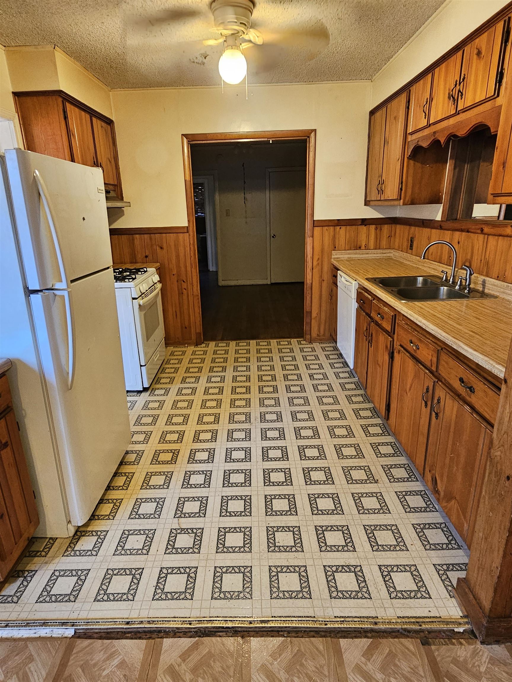 1196 Wells Station Road Memphis, TN 38122 - Photo 16 of 20 Kitchen with a textured ceiling, white appliances, light countertops, brown cabinetry, and ceiling fan