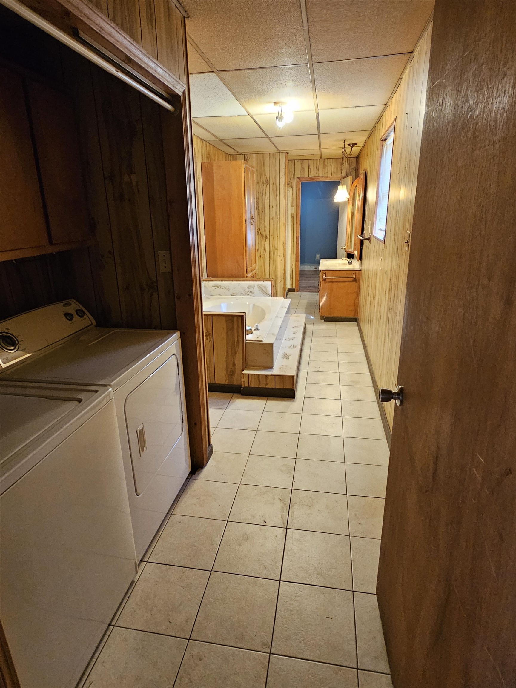 1196 Wells Station Road Memphis, TN 38122 - Photo 5 of 20 Laundry room featuring wooden walls, a drop ceiling, light tile patterned flooring, and independent washer and dryer