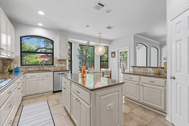 a kitchen with granite countertop a sink and white cabinets