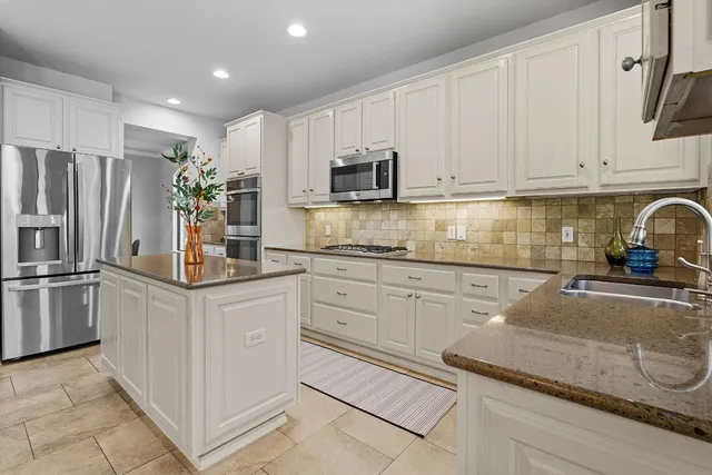 a kitchen with granite countertop white cabinets and stainless steel appliances