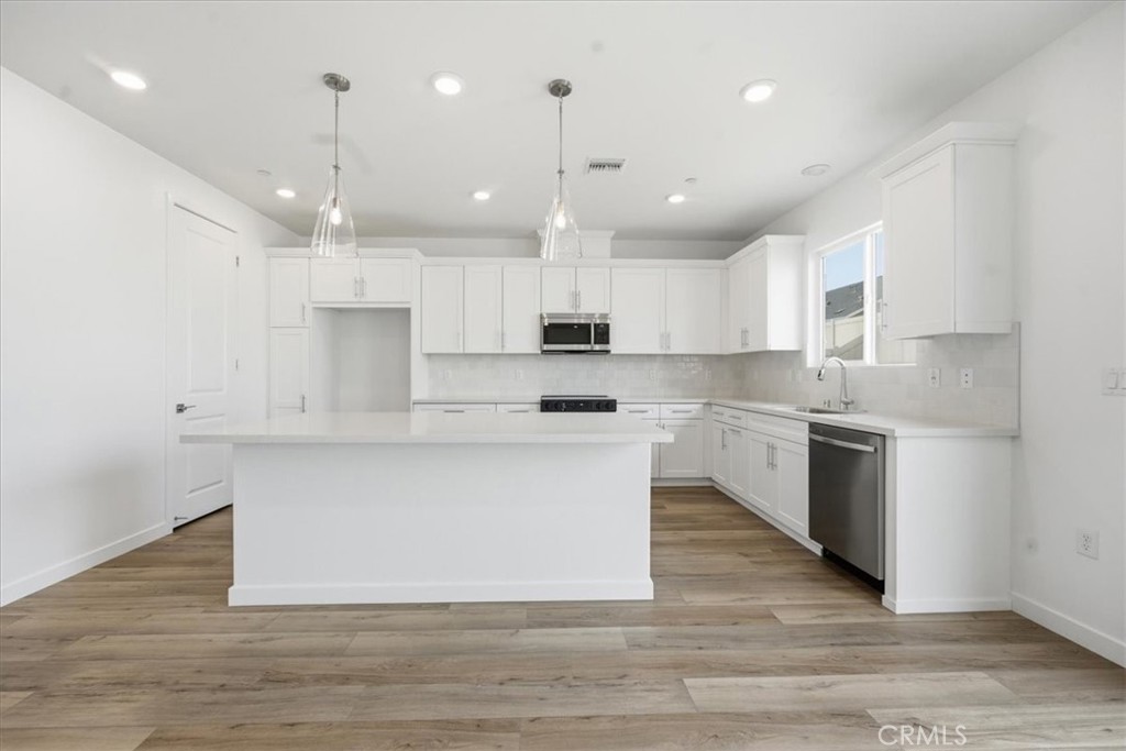 42957 56th Street West Lancaster, CA 93536 - Photo 11 of 40 a kitchen with kitchen island a sink stainless steel appliances and cabinets