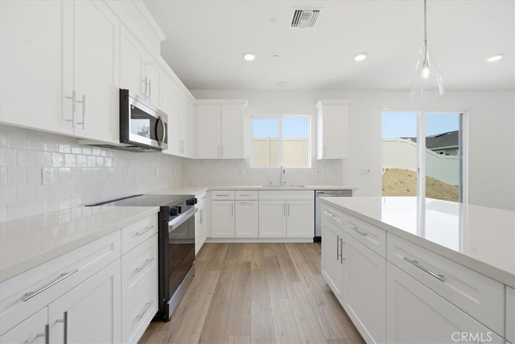 42957 56th Street West Lancaster, CA 93536 - Photo 13 of 40 a kitchen with granite countertop white cabinets and white appliances