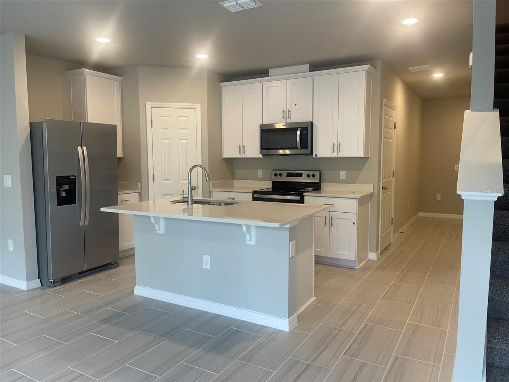 452 Legacy Loop Davenport, FL 33896 - Photo 7 of 29 a kitchen with stainless steel appliances a refrigerator stove microwave and sink