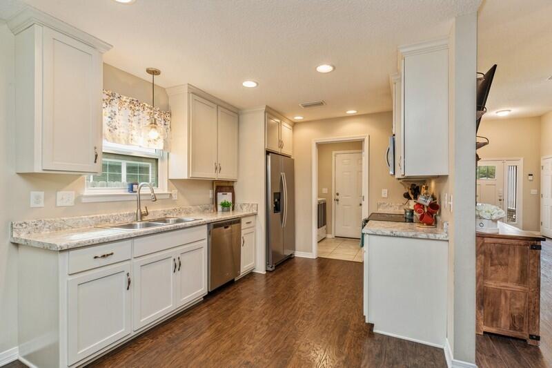 3152 Vaccari Court Crestview, FL 32539 - Photo 12 of 36 a kitchen with a sink dishwasher a refrigerator and white cabinets with wooden floor