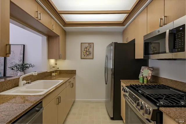 a kitchen with granite countertop a refrigerator stove and sink
