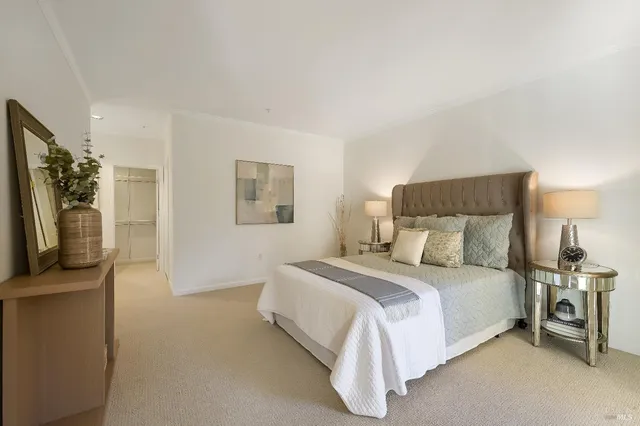 a bedroom with a bed a mirror and a flat tv screen on a dresser