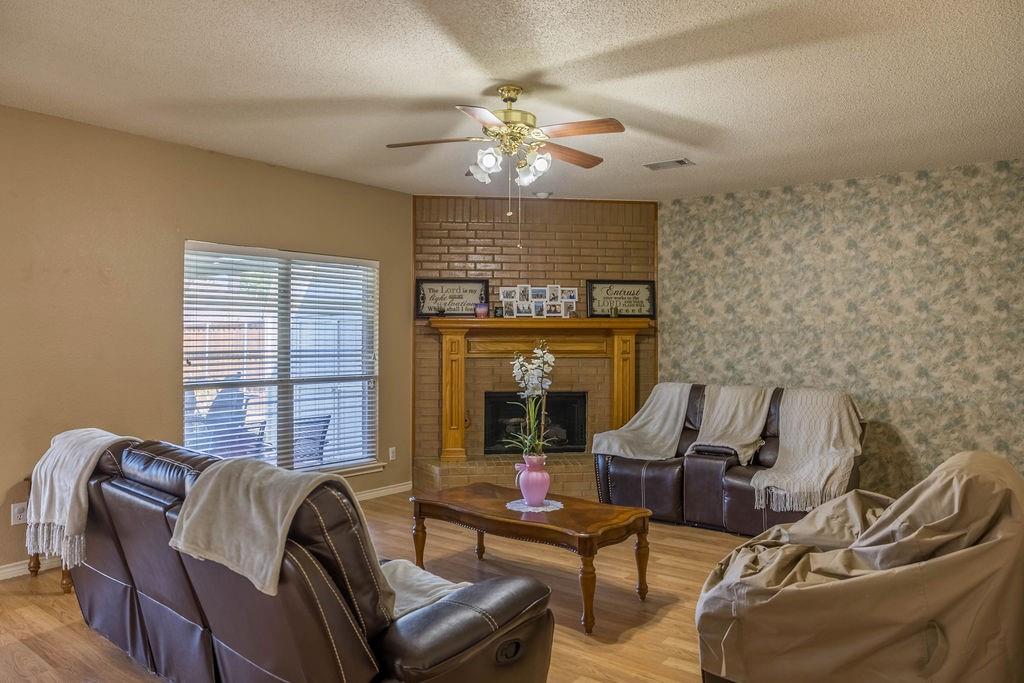 4113 Bluffpoint Road Rowlett, TX 75088 - Photo 11 of 39 Living area featuring a fireplace, a textured ceiling, light wood finished floors, and ceiling fan