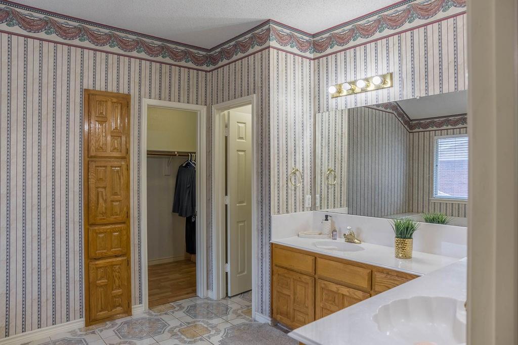 4113 Bluffpoint Road Rowlett, TX 75088 - Photo 20 of 39 Bathroom with a walk in closet, double vanity, wallpapered walls, and light tile patterned floors