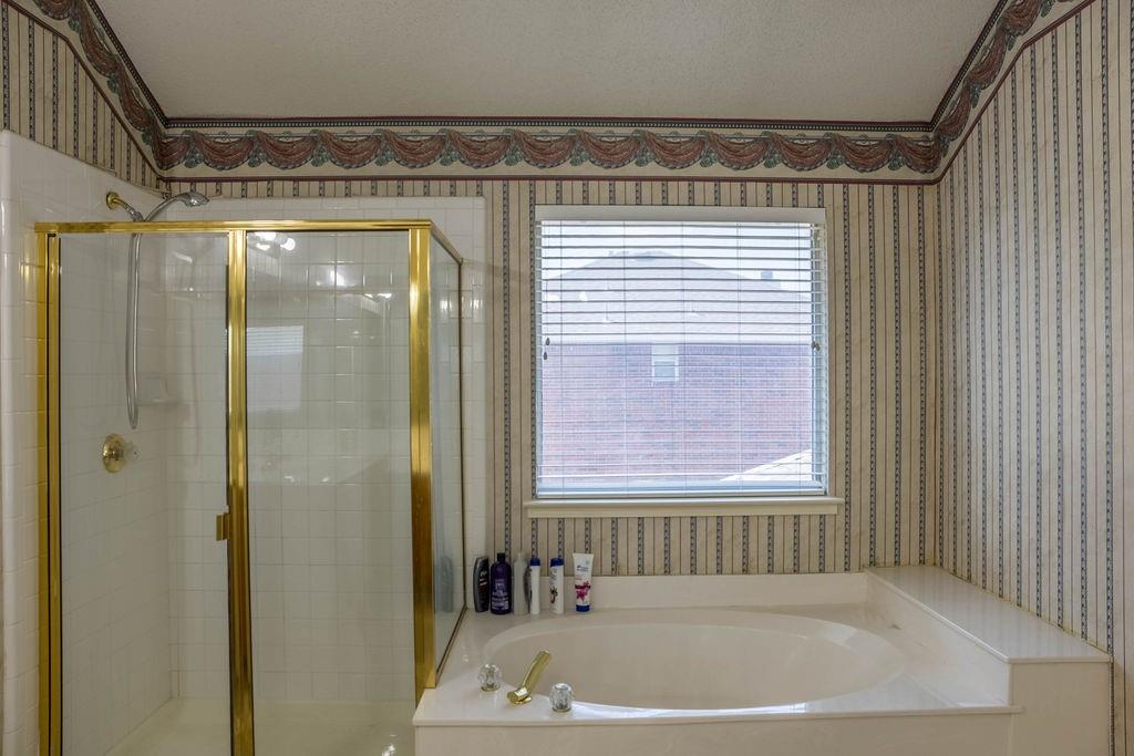 4113 Bluffpoint Road Rowlett, TX 75088 - Photo 21 of 39 Bathroom with wallpapered walls, a shower stall, and a bath