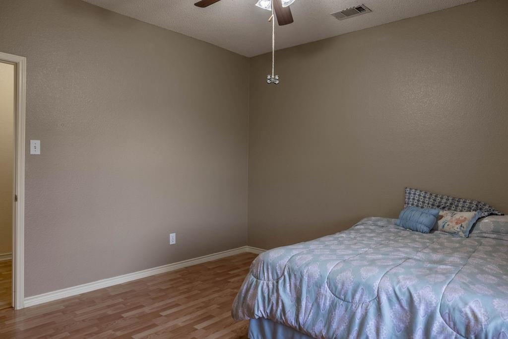 4113 Bluffpoint Road Rowlett, TX 75088 - Photo 27 of 39 Bedroom featuring wood finished floors, ceiling fan, and a textured ceiling