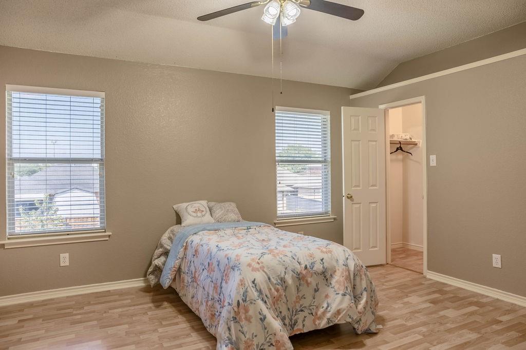 4113 Bluffpoint Road Rowlett, TX 75088 - Photo 28 of 39 Bedroom featuring light wood-type flooring, a walk in closet, lofted ceiling, and ceiling fan