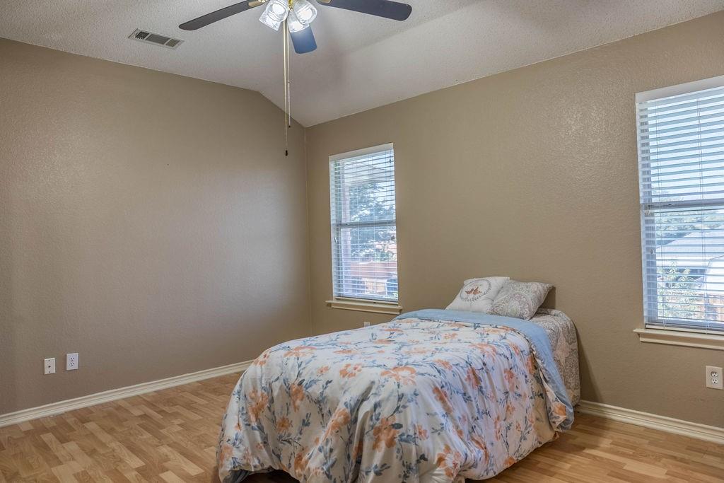 4113 Bluffpoint Road Rowlett, TX 75088 - Photo 29 of 39 Bedroom featuring light wood-style floors, vaulted ceiling, ceiling fan, and a textured wall