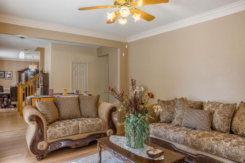 4113 Bluffpoint Road Rowlett, TX 75088 - Photo 5 of 39 Living area with crown molding, wood finished floors, ceiling fan, and stairway