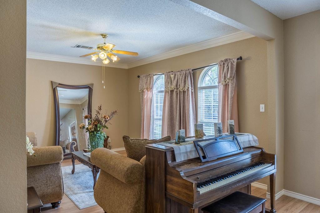 4113 Bluffpoint Road Rowlett, TX 75088 - Photo 6 of 39 Living area featuring light wood-style floors, crown molding, a ceiling fan, and a textured ceiling