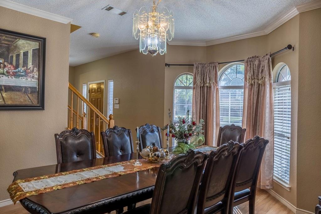 4113 Bluffpoint Road Rowlett, TX 75088 - Photo 10 of 39 Dining area with light wood-style flooring, a textured ceiling, ornamental molding, stairs, and a chandelier
