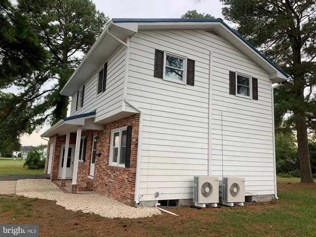 a view of a white house with a yard and large tree