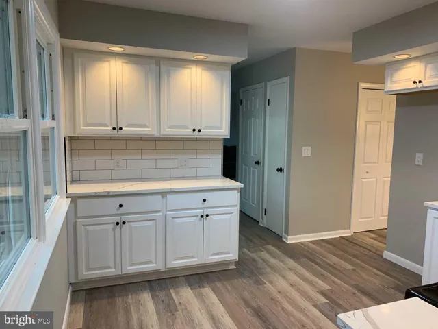 a kitchen with white cabinets and wooden floors