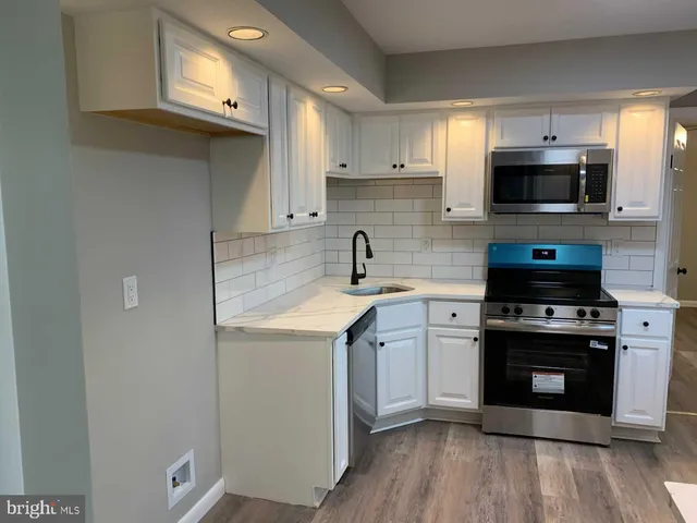 a kitchen with stainless steel appliances white cabinets a sink and a stove