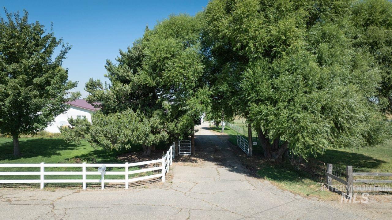 23626 Boise River Road Caldwell, ID 83607 - Photo 2 of 49 Property featuring a metal roof, expansive green lawn, and mature trees