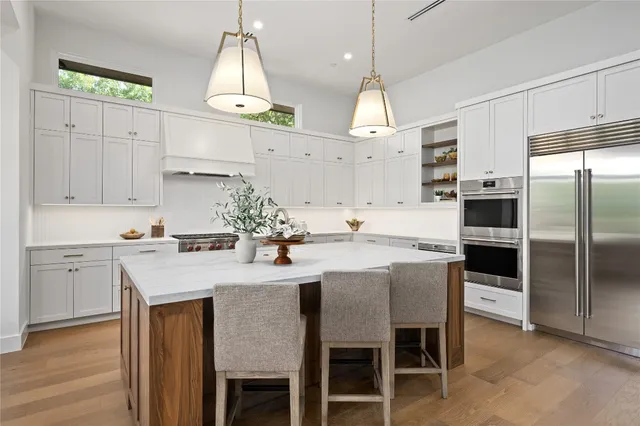 a kitchen with kitchen island a dining table chairs stainless steel appliances and cabinets