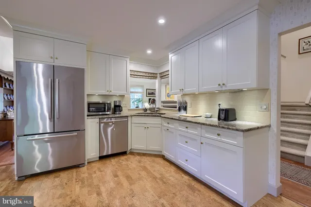 a kitchen with granite countertop stainless steel appliances a refrigerator a stove top oven and cabinets