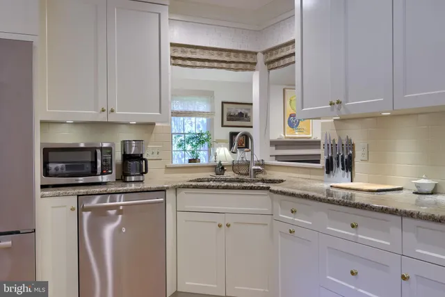a kitchen with granite countertop white cabinets and white appliances
