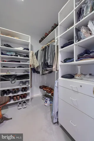 a view of walk in closet with clothes and shoes