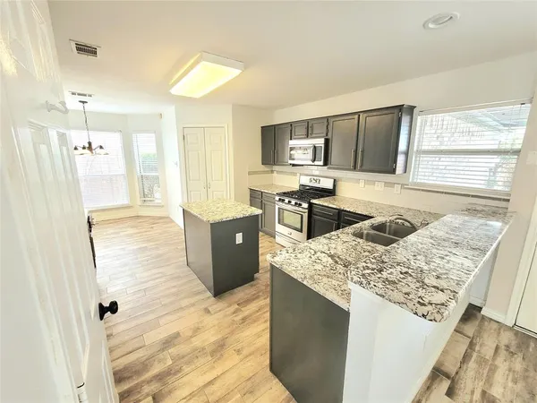 a kitchen with kitchen island granite countertop a sink stove and refrigerator