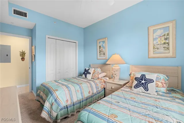 a bedroom with two beds and a lamp on dresser