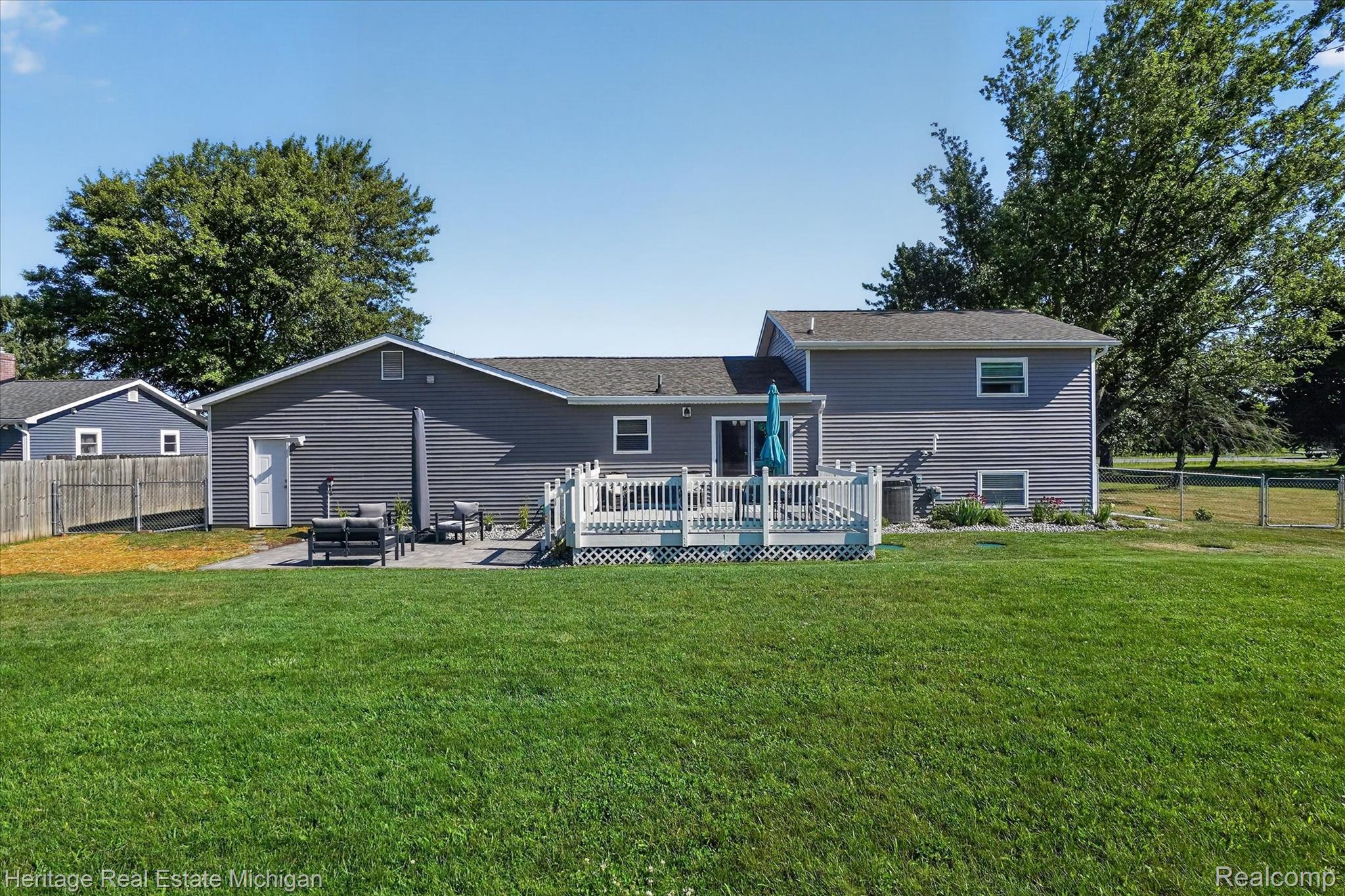 7225 Baldwin Road Swartz Creek, MI 48473 - Photo 33 of 44 Manicured green lawn with a composite deck, sliding glass door access, and a stone paver patio