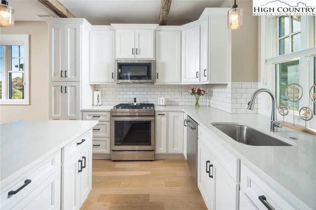 a kitchen with stainless steel appliances granite countertop a stove a sink dishwasher and a refrigerator with wooden floor