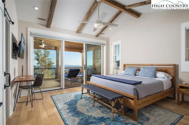 a bedroom with a bed and large window with balcony view