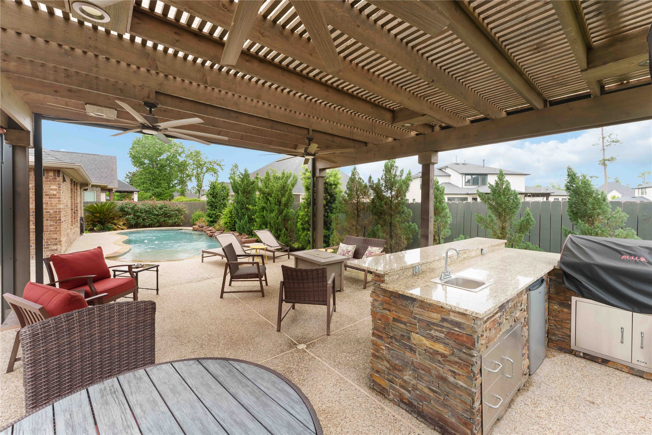 10127 Cooper's Hawk Way Conroe, TX 77385 - Photo 26 of 35 The pergola is smartly equipped with an outdoor kitchen, beverage cooler, plenty of space for relaxing, and motorized screens that offer privacy and year round enjoyment.