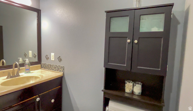 1797 Sunset Road Enoch, UT 84721 - Photo 26 of 80 Vanity with integrated sink, dark wood-finish cabinetry, and a mosaic tile backsplash